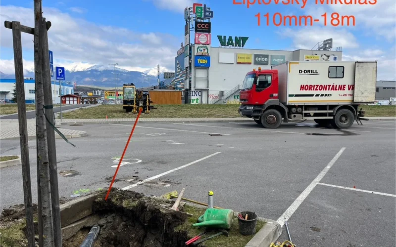 Jama v zelenom páse pri parkovisku obchodnej zóny v Liptovskom Mikuláši, v pozadí vozidlo D-Drill.
