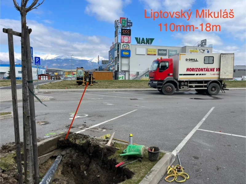 Jama v zelenom páse pri parkovisku obchodnej zóny v Liptovskom Mikuláši, v pozadí vozidlo D-Drill.