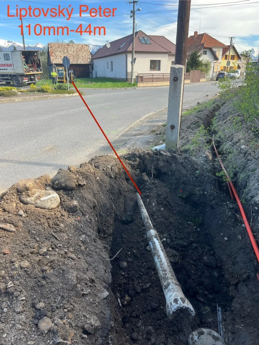 Potrubie zatiahnuté popod miestnu komunikáciu v obci Liptovský Peter, ryha pri krajnici.