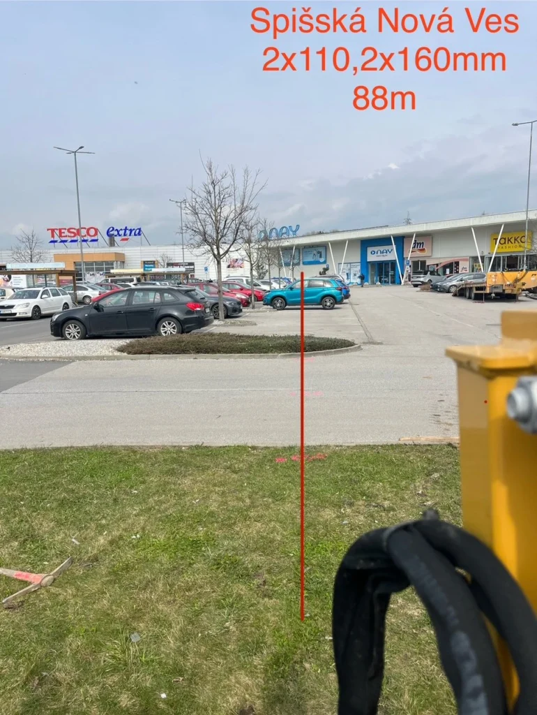 Vrtná súprava na trávnatom ostrovčeku, trasa pretlaku vedie popod parkovisko nákupného centra v Spišskej Novej Vsi.